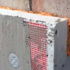 Fragment ocieplenia fundamentów z siatką zbrojeniową i pianką montażową.