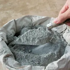 Łopatka nabiera cement do wylewki z worka. Ile łopat piasku na worek cementu do wylewki?