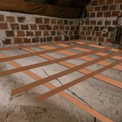 Drewniana konstrukcja podłogi na betonowym podłożu, przygotowana pod wylewkę na płytę OSB.