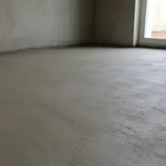 Świeżo wylana podłoga cementowa w pustym pomieszczeniu z oknem.