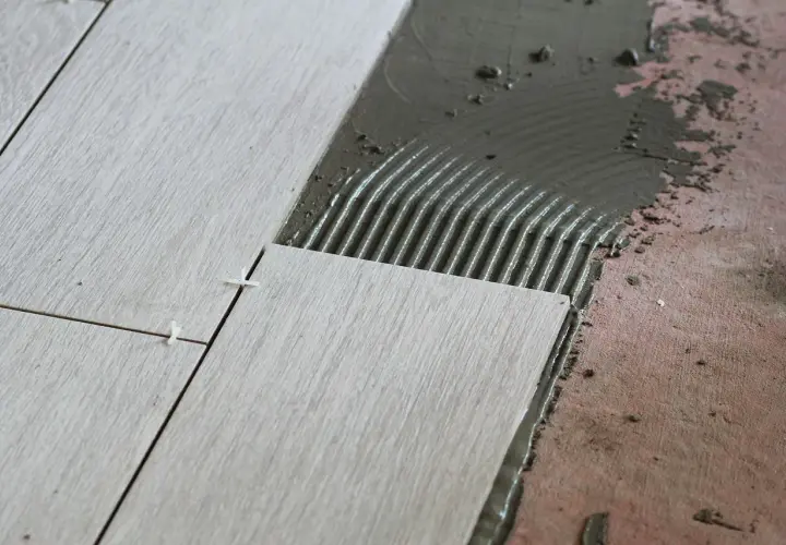Układanie płytek 60x60. Cennik prac glazurniczych. Widać świeżą zaprawę klejową i precyzyjne rozmieszczenie płytek.