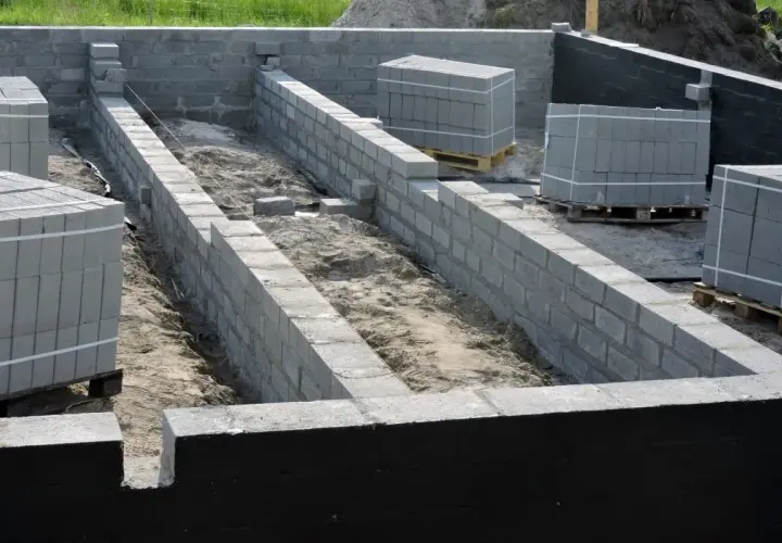 Fundament budowy z bloczków betonowych, przygotowany do prac związanych z hydroizolacją.