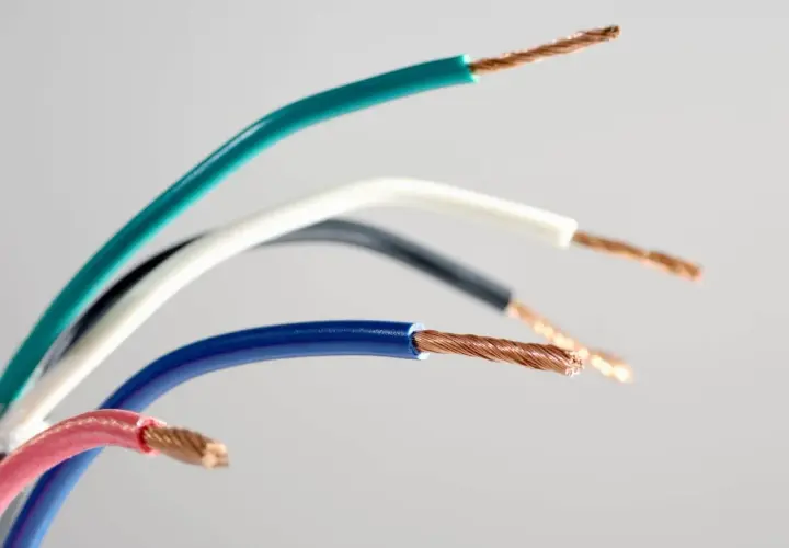 Kilka kolorowych przewodów elektrycznych, w tym zielony, biały, czarny, niebieski i czerwony, z odsłoniętymi miedzianymi końcówkami. Jeden z przewodów, niebieski, jest wyraźnie widoczny, a obok niego znajduje się przewód neutralny.