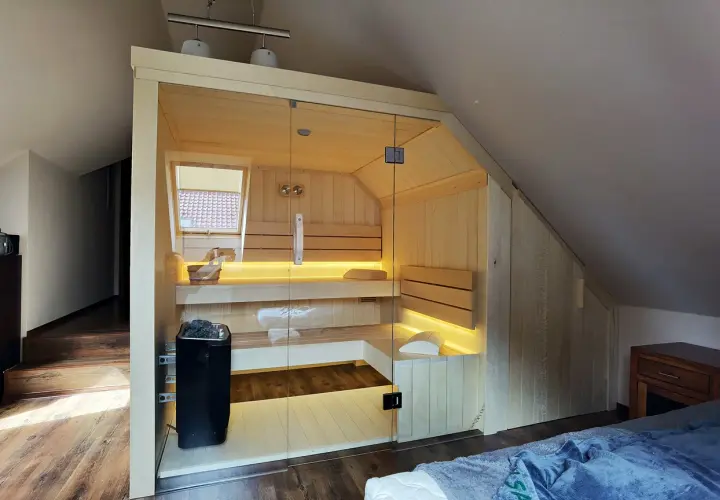 Nowoczesna sauna w domu, z przeszklonymi drzwiami i nastrojowym oświetleniem. Idealne miejsce na relaks po całym dniu.