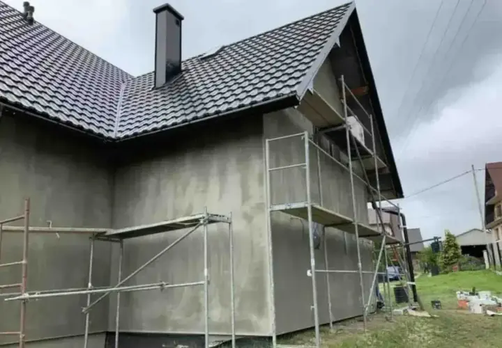 Dom w trakcie prac elewacyjnych. Rusztowanie wokół nieotynkowanej ściany. Sprawdzamy elewacja cena za m2 robocizna.