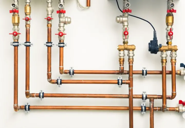 System hydrauliczny z miedzianymi rurami i zaworami. Różnica między złączkami PEX U czy TH jest kluczowa dla szczelności instalacji.