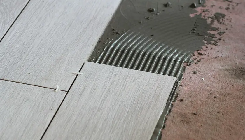 Układanie płytek 60x60. Cennik prac glazurniczych. Widać świeżą zaprawę klejową i precyzyjne rozmieszczenie płytek.