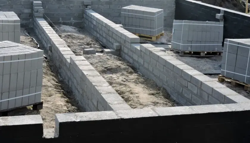 Fundament budowy z bloczków betonowych, przygotowany do prac związanych z hydroizolacją.