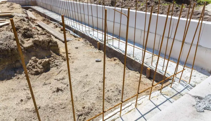 Przygotowanie zbrojenia fundamentu pod budowę. Stalowe pręty tworzą siatkę, która wzmocni beton.