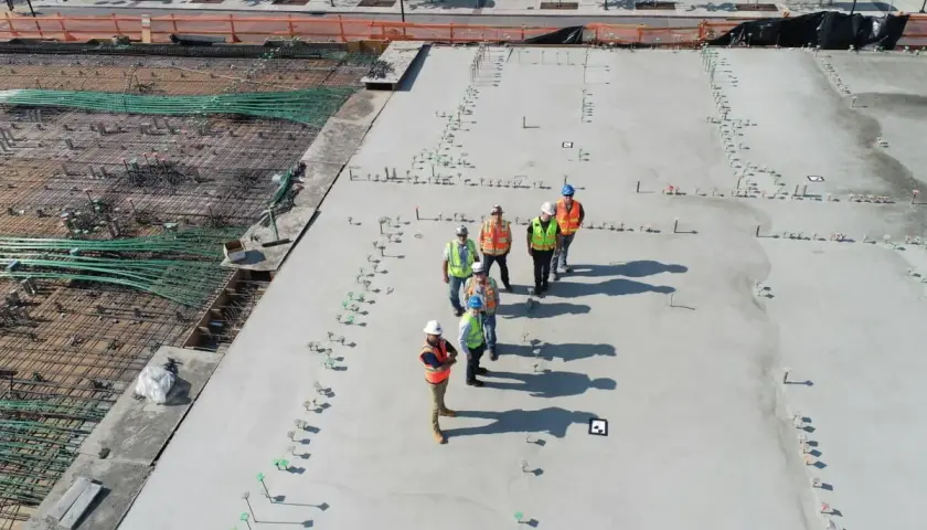 Grupa budowlańców na placu budowy. Widać zbrojenie i świeży beton. Sprawdzają beton b25 cena za m3.