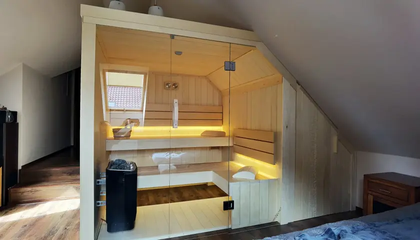 Nowoczesna sauna w domu, z przeszklonymi drzwiami i nastrojowym oświetleniem. Idealne miejsce na relaks po całym dniu.