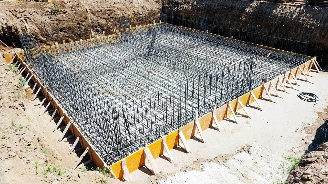 Siatka zbrojenia fundamentu w wykopie, gotowa do zalania betonem. Solidna podstawa przyszłego budynku.